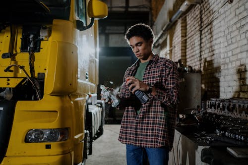 Man Wearing Plaid Long Sleeves Polo Holding a Spray Can