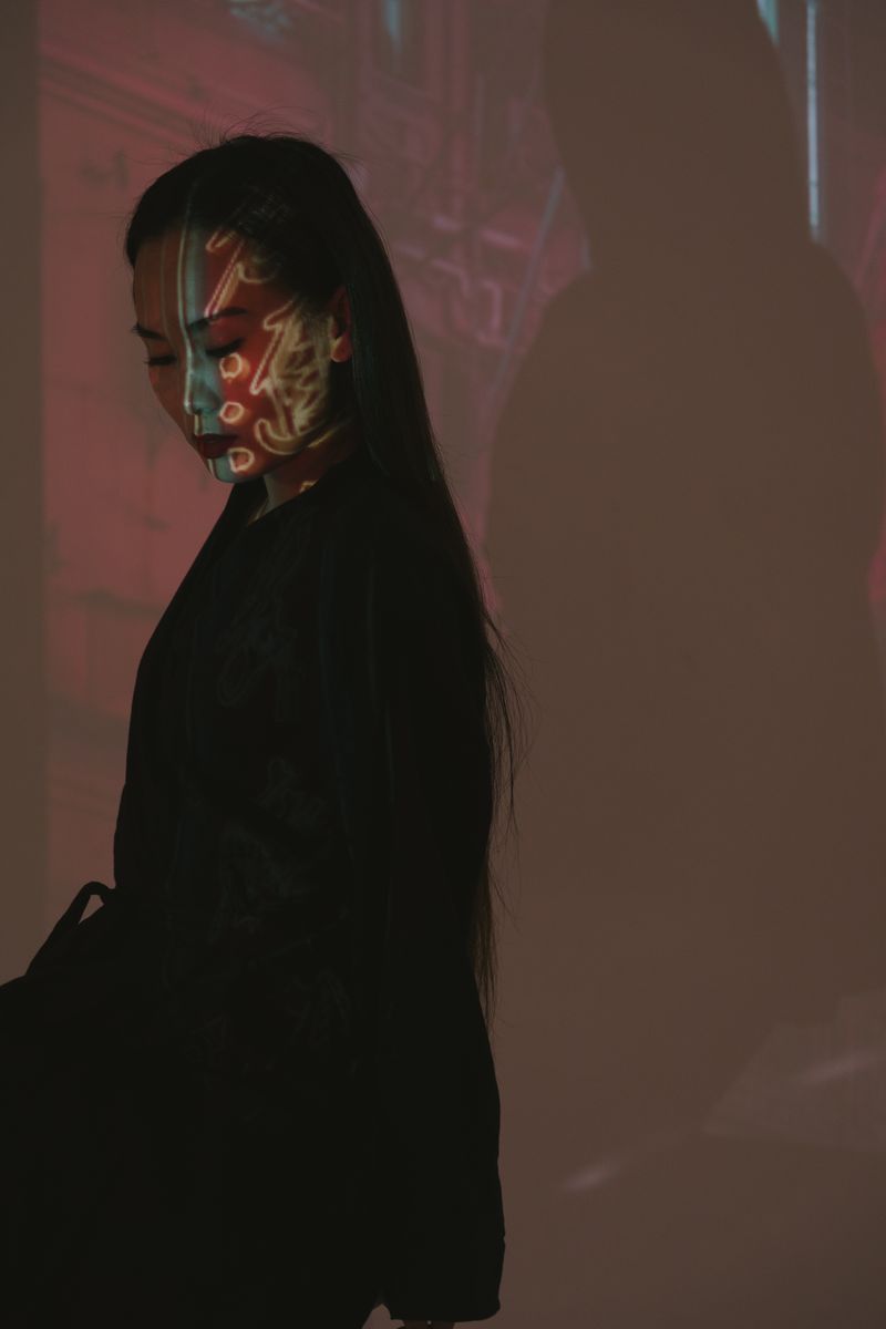 A woman in a studio with colorful light projections across her face