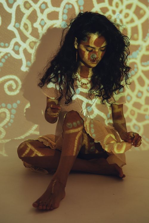 Free Woman with intricate projection art sitting on the floor. Stock Photo