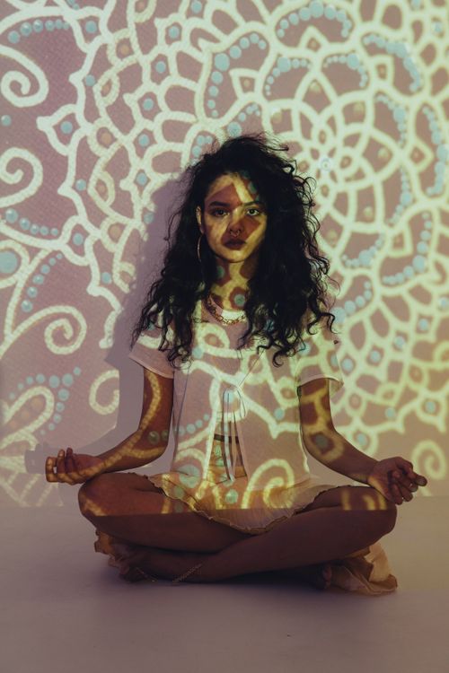 Free Woman meditating with intricate mandala projections around her, embracing peace and tranquility. Stock Photo