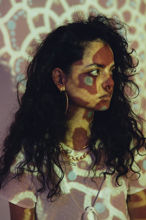 A Woman Wearing White Shirt and Jewelries in Front of the Projector Light