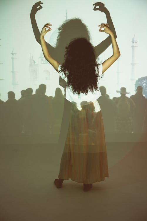 A Woman Raising Her Hand in Front of a Projector Light