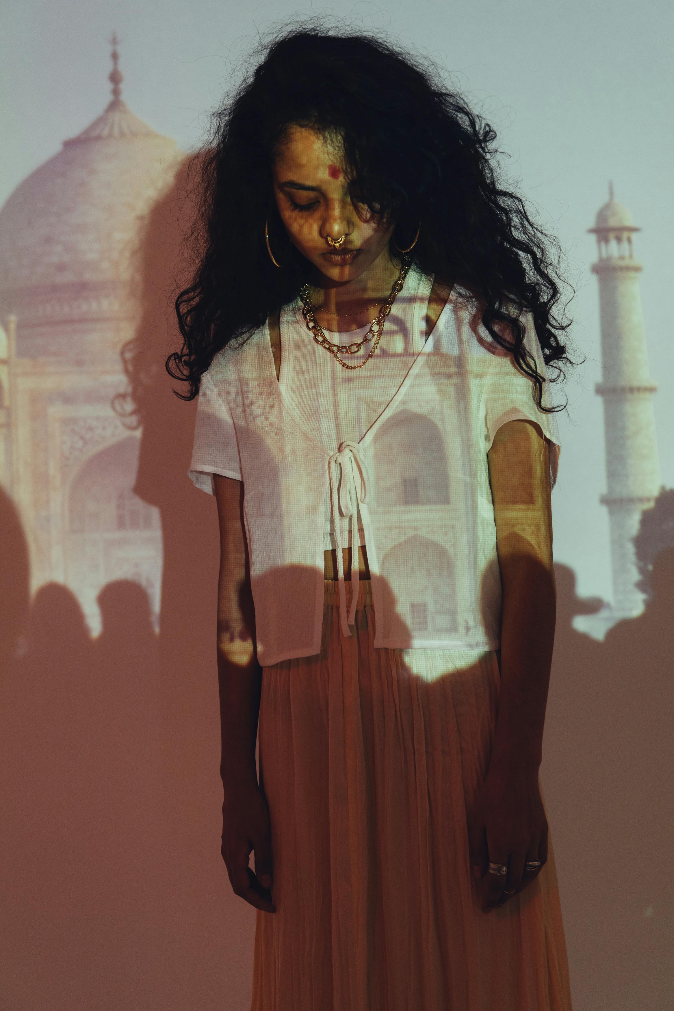 Woman in Yellow and White Button Up Shirt Standing Beside Red Wall