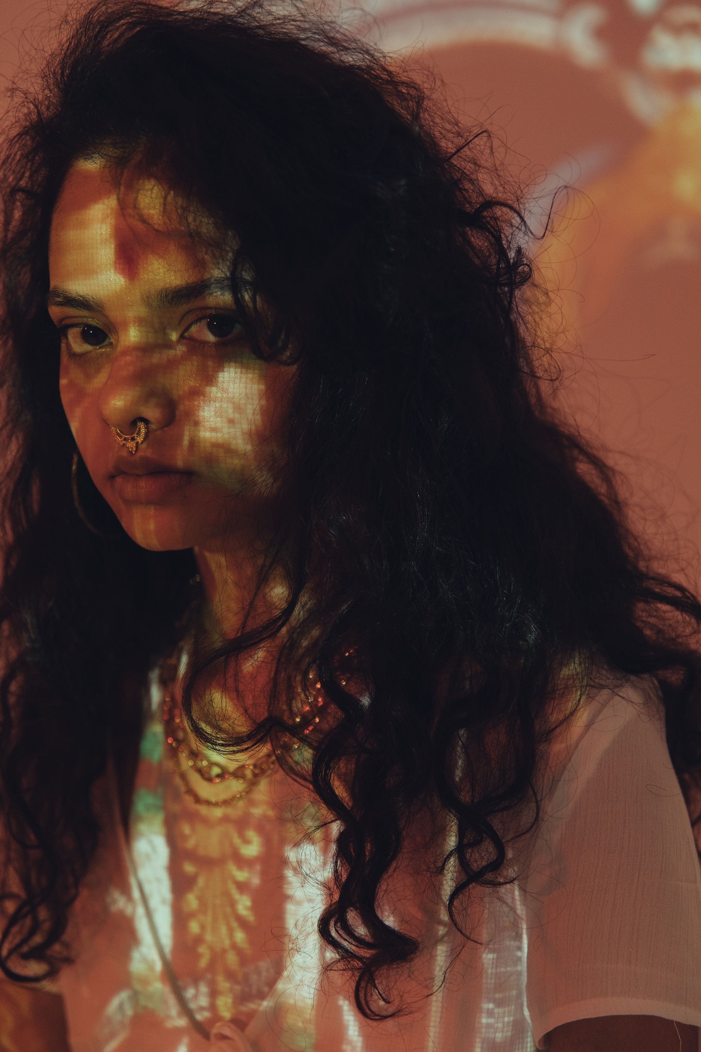 Artistic portrait of a woman with intricate projections on her face, evoking a mysterious and moody atmosphere.