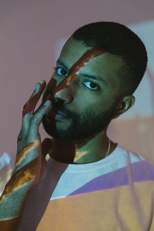 Free Creative portrait of a man with artistic light projections casting shadows on his face. Stock Photo