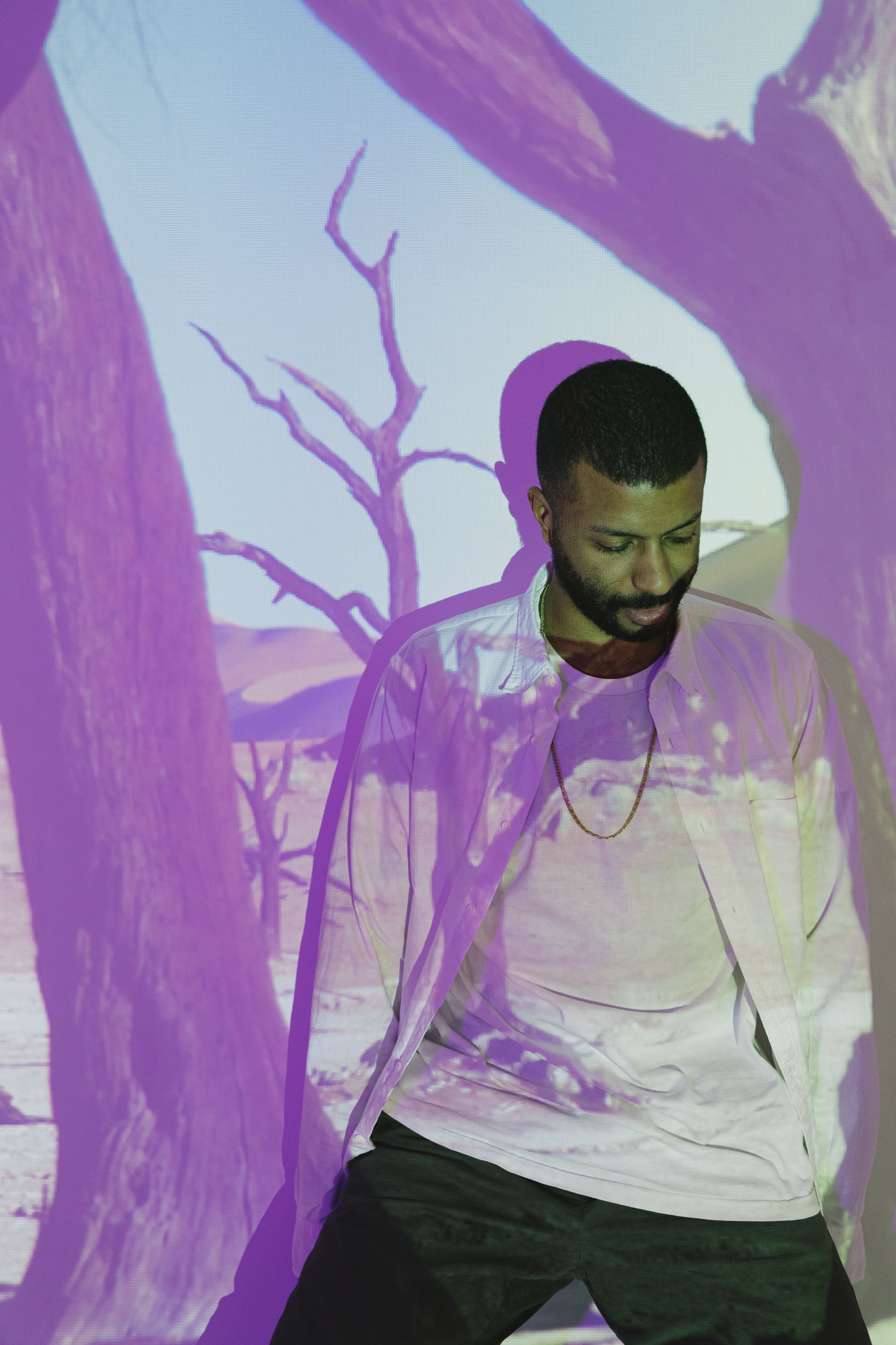 Man stands with desert scene projection on him, creating a striking artistic effect.