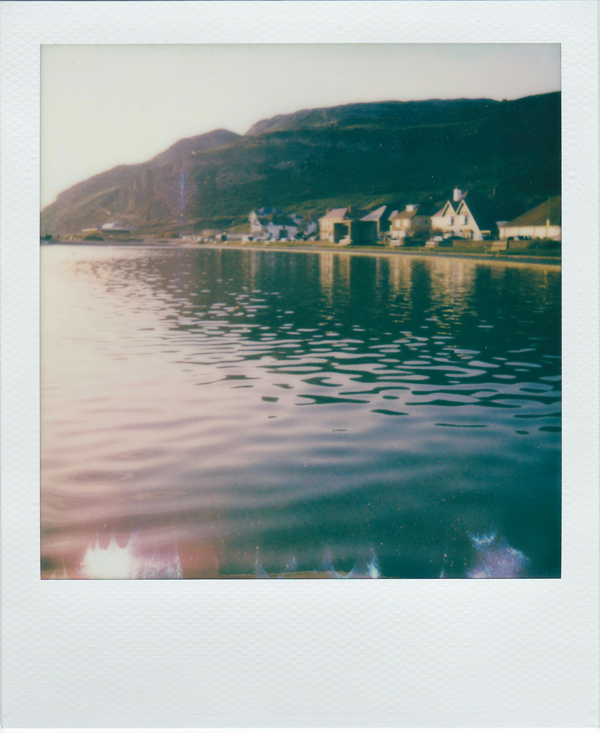A serene lakeside village with reflections and mountain backdrop.