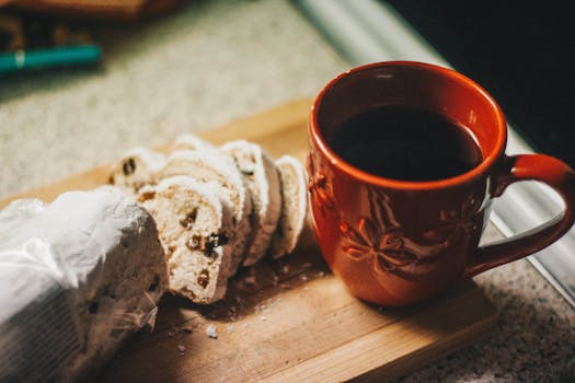 A cozy scene of a cup of black coffee and sliced raisin bread on a wooden board.