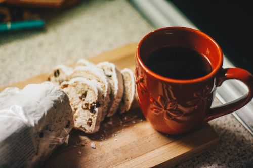 Free A cozy scene of a cup of black coffee and sliced raisin bread on a wooden board. Stock Photo