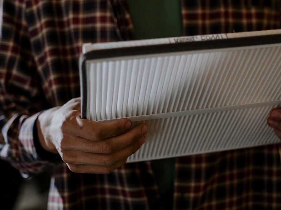Hands holding a clean white pleated air filter