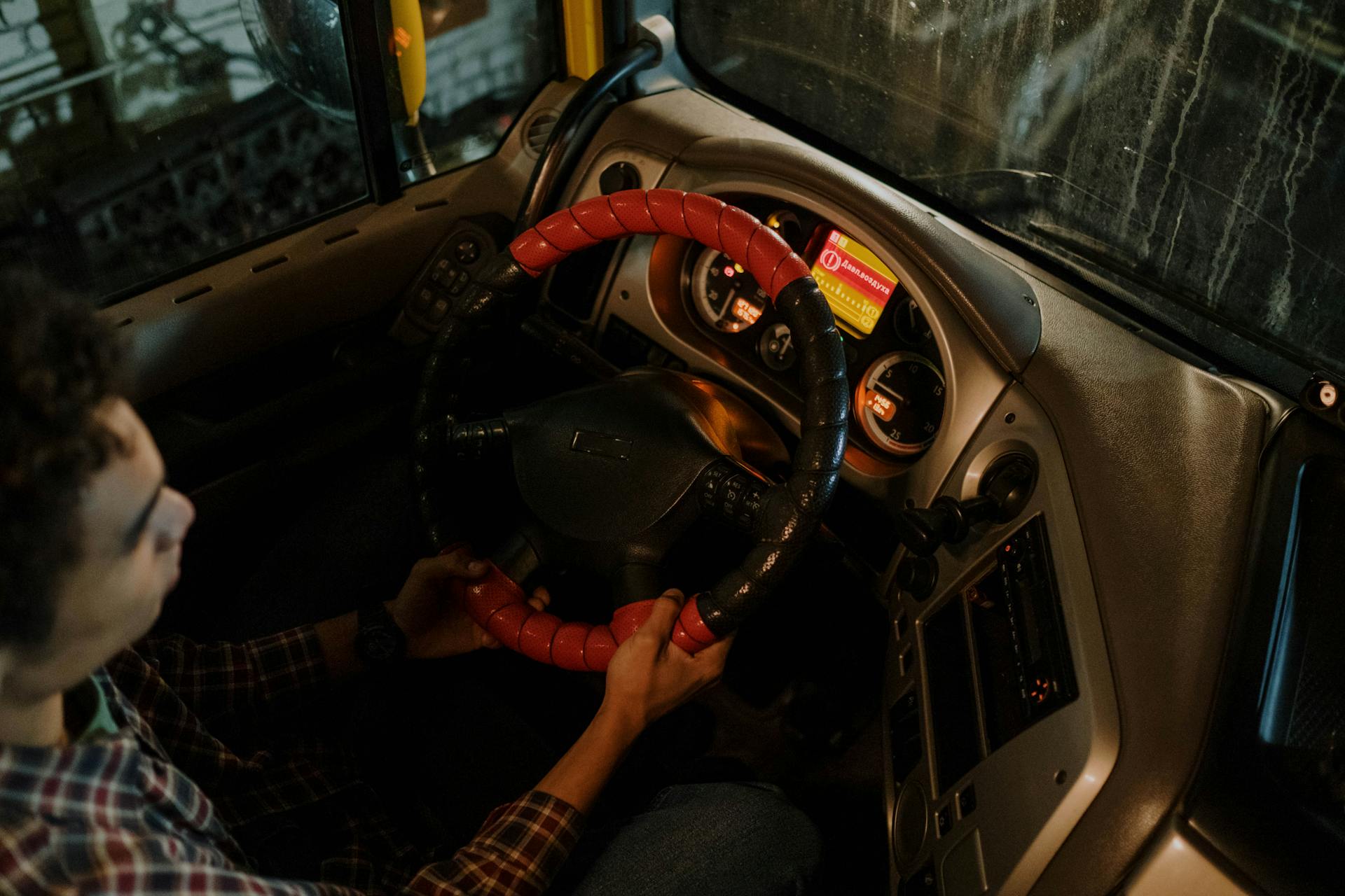 Interior view of a car dashboard and driver focused on steering at night.