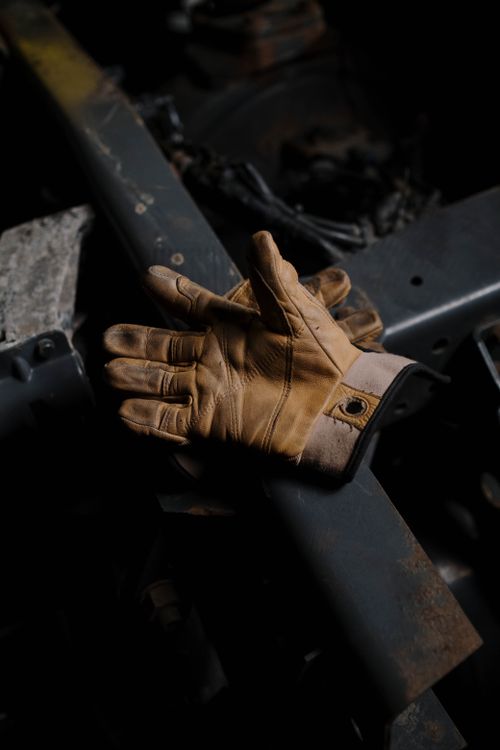 Free Brown leather gloves resting on an industrial steel surface, showcasing craftsmanship and durability. Stock Photo