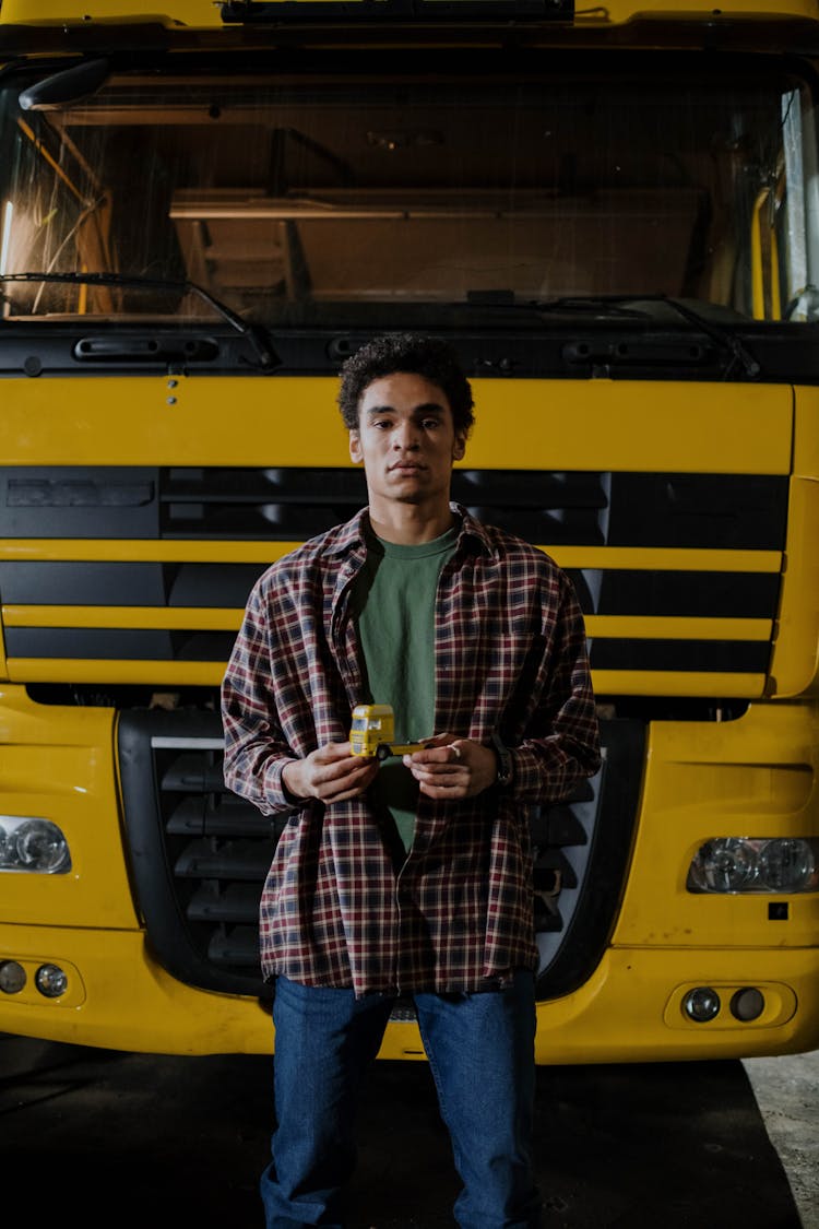 Man In Plaid Shirt Standing In Front Of Big Yellow Vehicle