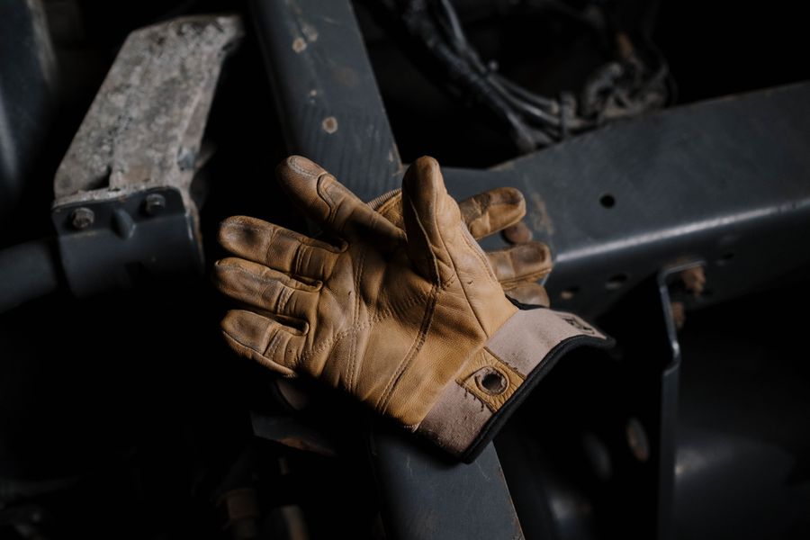 Worn leather work gloves resting on heavy machinery