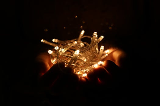 Hands holding glowing LED string lights, creating a warm and festive atmosphere.