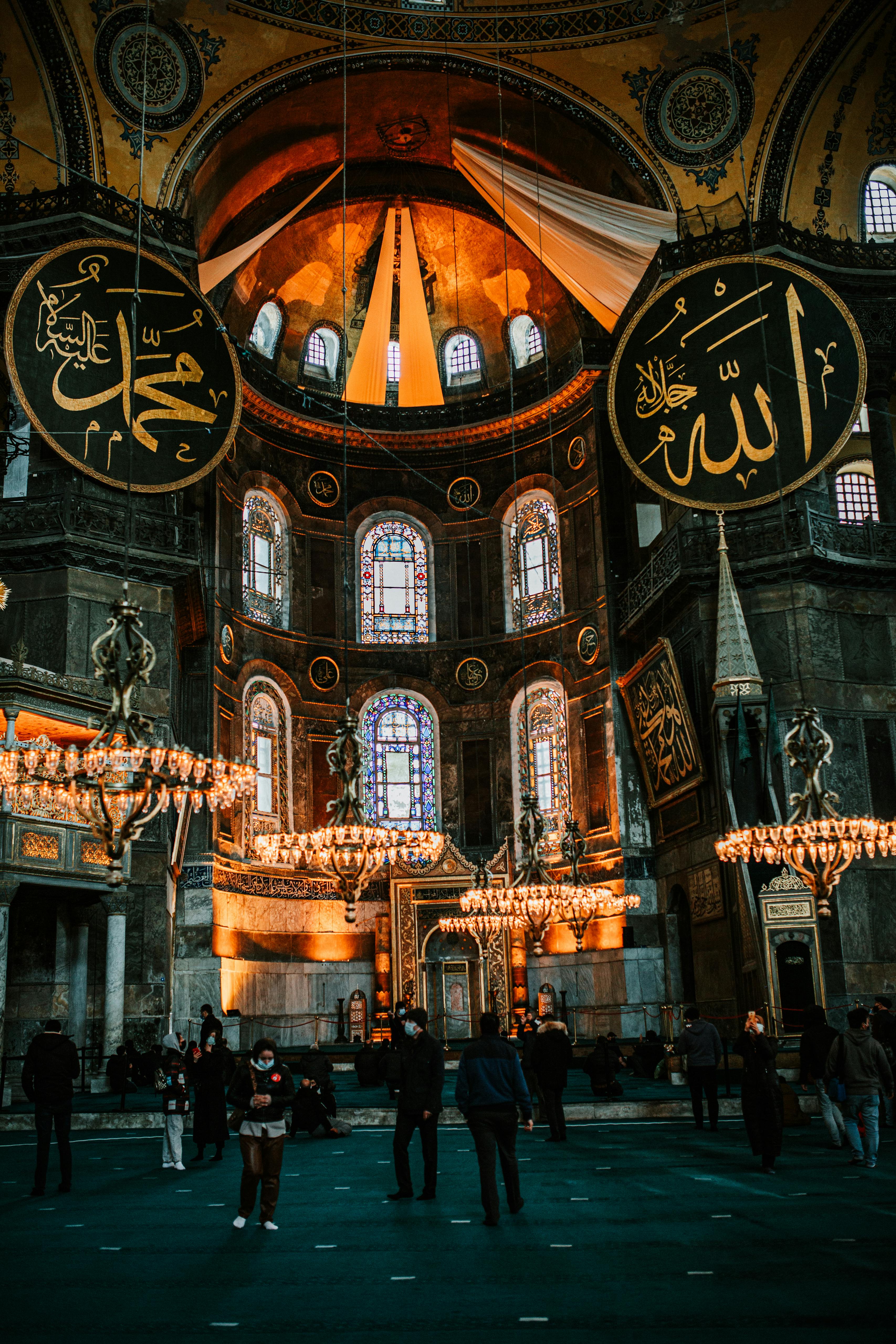 arched stained glass windows and glowing chandeliers inside of historic mosque