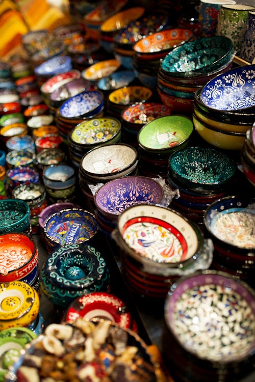 From above of colorful handmade ornamental ceramic bowls placed in row on stall in local market