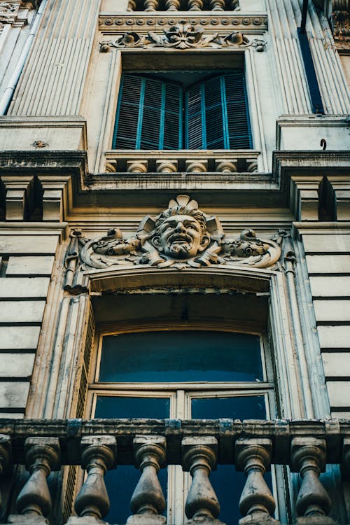 Free Facade of old building with sculptures and shuttered windows Stock Photo