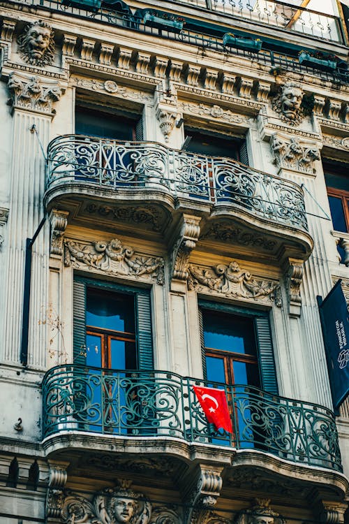 Turkish flag hanging on balcony of old residential building decorated with sculptures