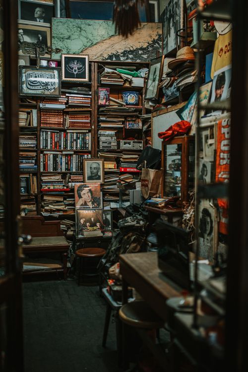 Free Storage for large collection of various books and paintings near wooden table with laptop and chair Stock Photo