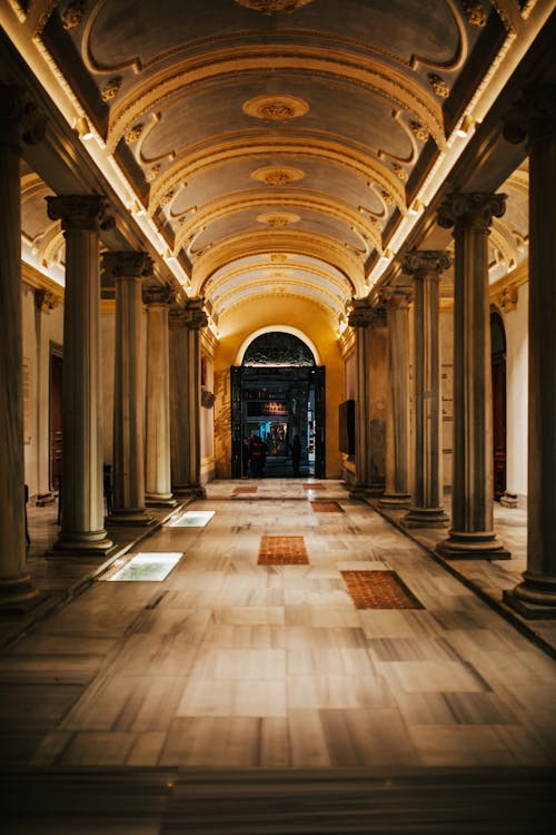 Interior of spacious empty corridor with tall columns on white floor and ornamental details on ceiling