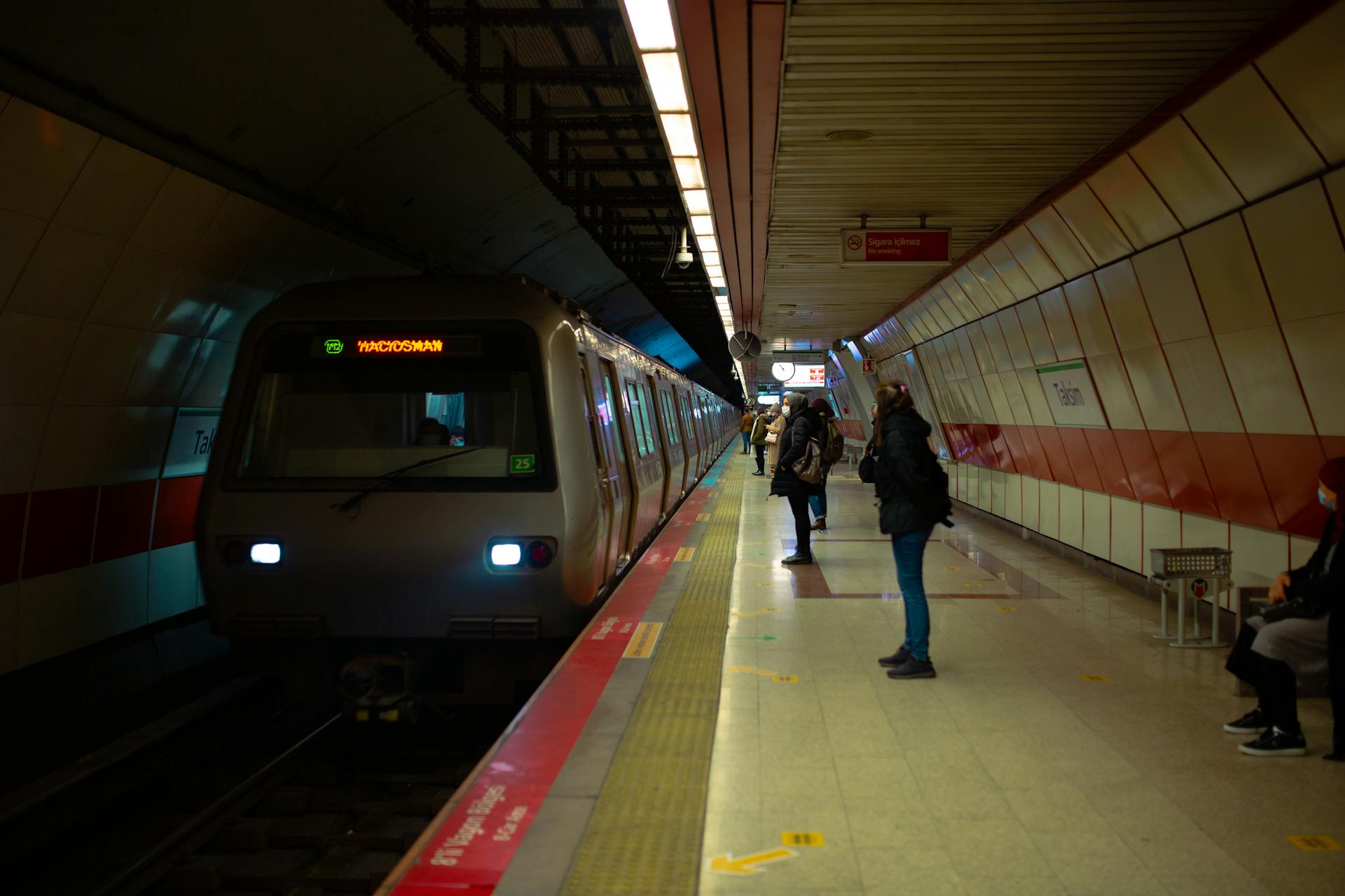 Light platform of subway with people in outerwear waiting for modern train driving on railroad