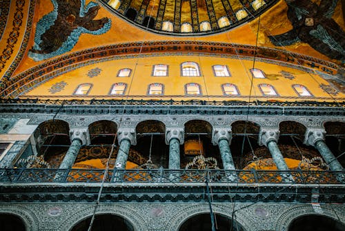 From below of aged stone columns and arched windows under ornamental dome in Hagia Sophia Mosque in Turkey