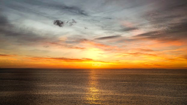 A serene ocean sunset with vivid colors reflecting on calm waters.