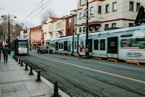 Modern tram driving along railroad on street with buildings in city in evening time