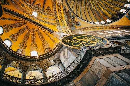 From below of decorated dome with ornamental details inside of mosque in daylight