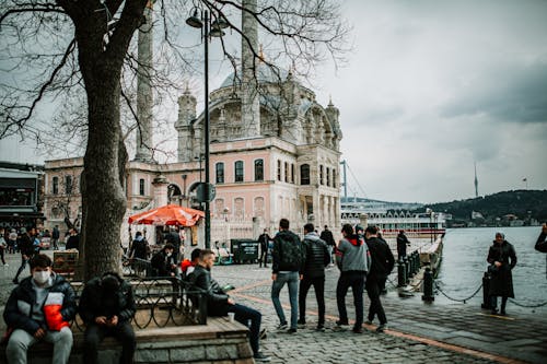 People walking on square near Grand Imperial Mosque of Sultan Abdulmecid in Ortakoy under cloudy sky in daytime