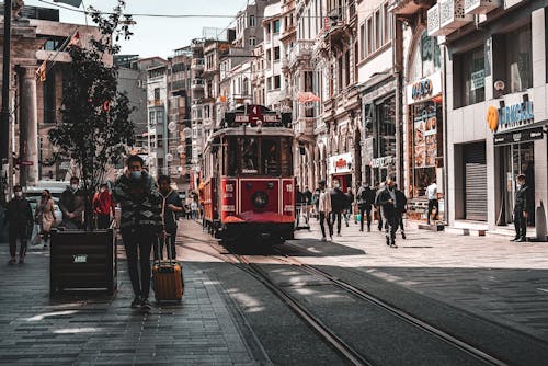 People Walking on Road Near Red Tram