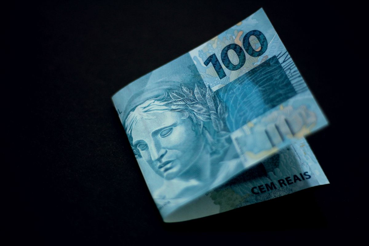 Notas de R$ 100 reais empilhadas representando finanças pessoais no Brasil