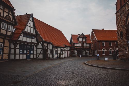 Free A quaint cobblestone street in a European town showcasing vintage houses with red roofs. Stock Photo
