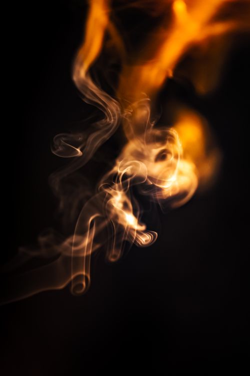 Free Dynamic orange and white smoke captured against a black background, creating an abstract and mysterious effect. Stock Photo