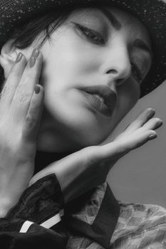 Artistic grayscale close-up portrait of a fashionable woman in thoughtful pose.