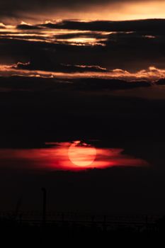 A vivid sunset casting vibrant colors behind silhouetted clouds, creating a striking skyscape.