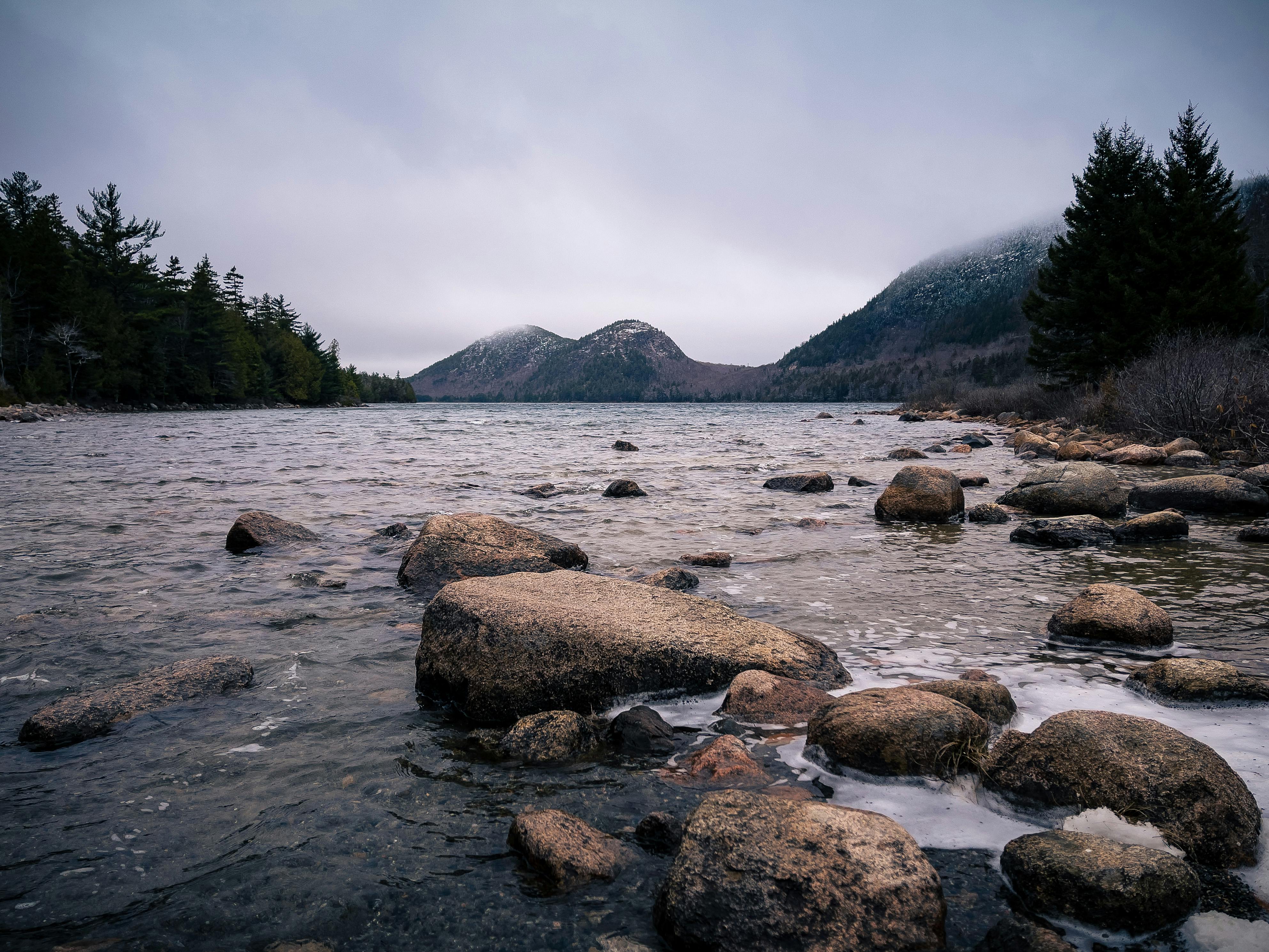 Wild rocky river flowing in mountainous terrain against foggy sky