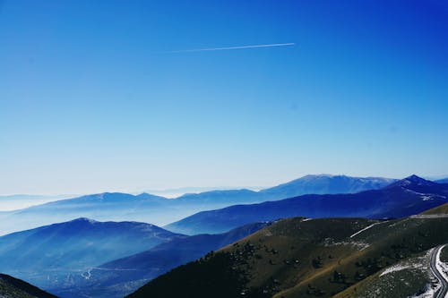 Зеленый и синий туман покрытые горы под голубым небом