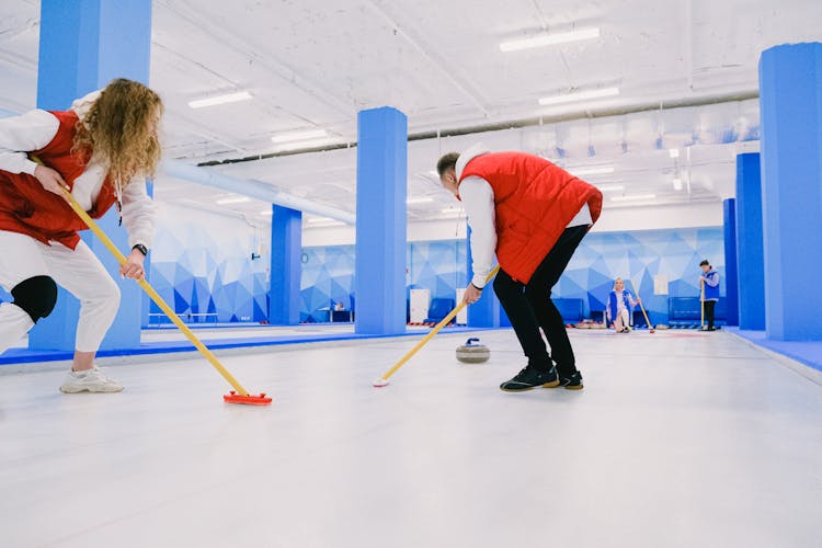 Team Playing Curling On Ice Sheet