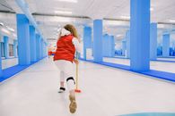 Active woman playing curling on ice rink