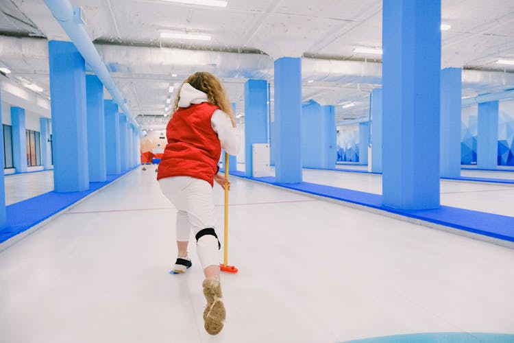 Active Woman Playing Curling On Ice Rink