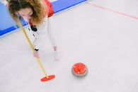 Woman playing curling on ice sheet