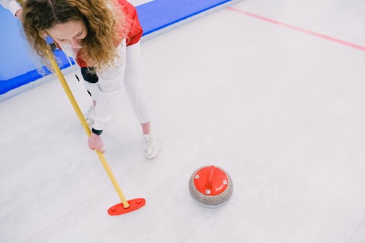 Woman Playing Curling On Ice Sheet