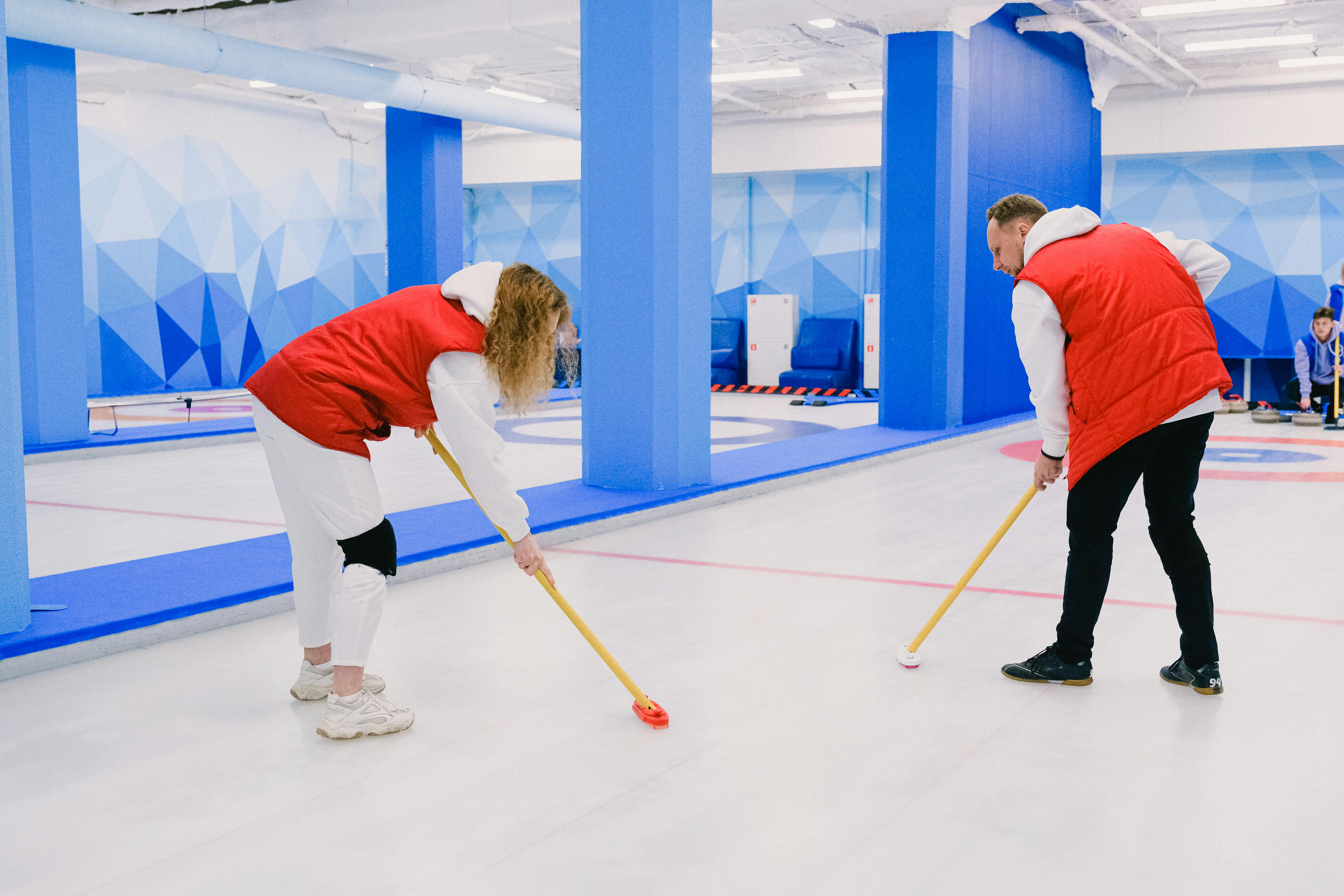 Players sweeping ice during curling game · Free Stock Photo