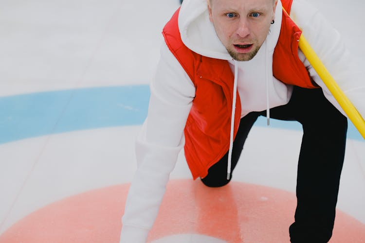 Determined Sportsman Playing Curling On Ice Rink