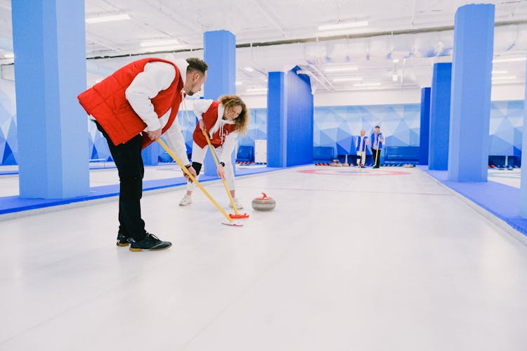 Players In Uniform Playing Curling On Modern Ice Rink