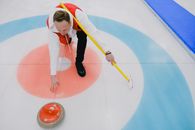 From above of concentrated sportsman in activewear throwing stone during curling competition on ice rink in daytime