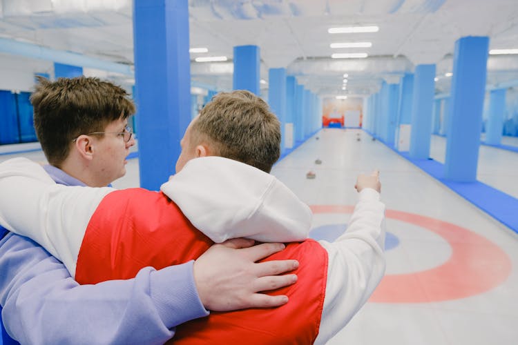 Sportsmen Playing Curling On Modern Ice Rink