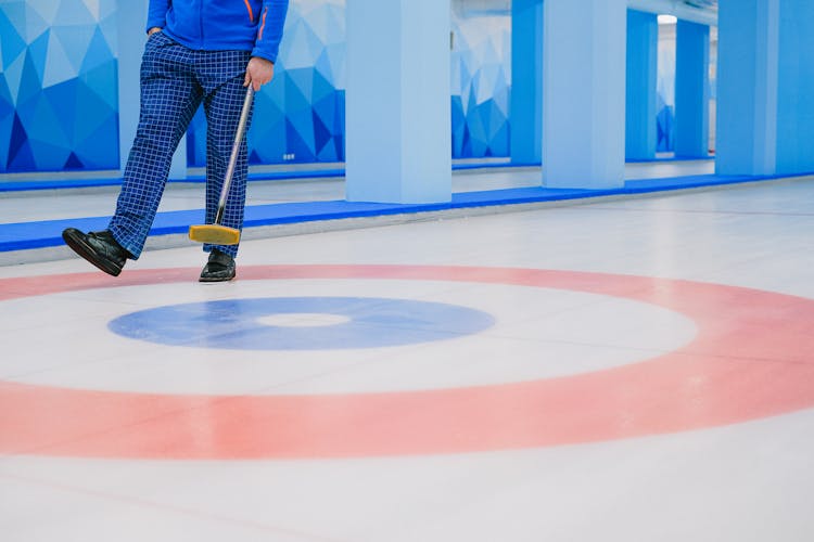 Sportsman With Broom Stick Walking On Ice Rink